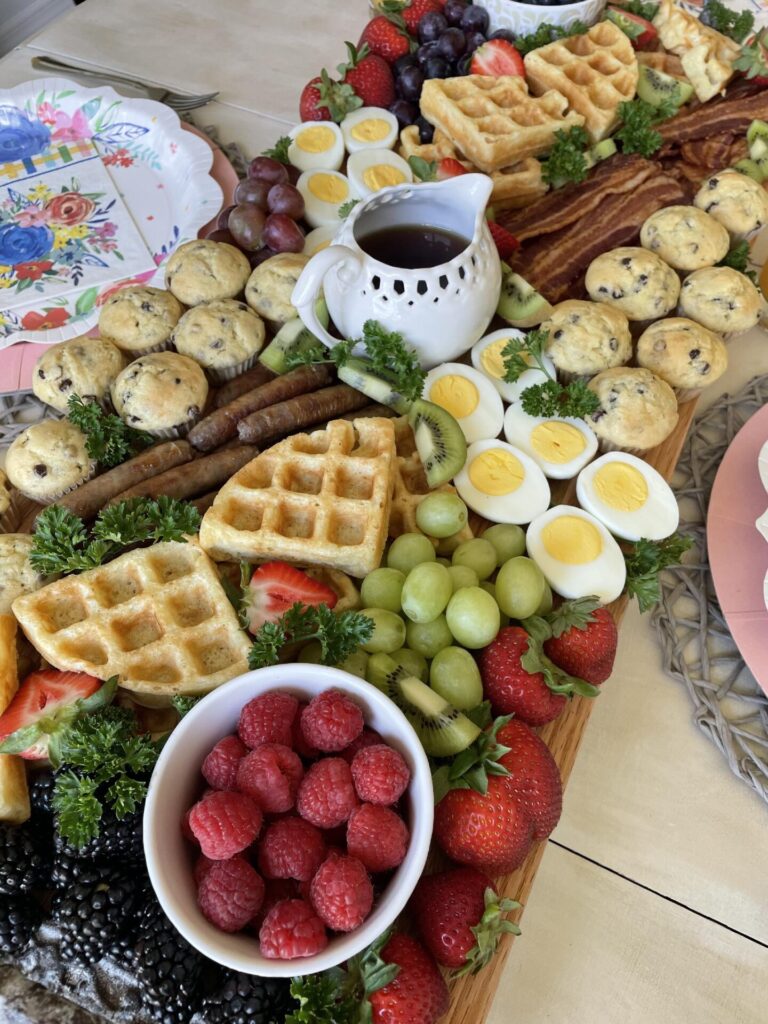 DIY breakfast board filled with bacon, sausage, mini muffins, hard boiled eggs and fruit for Mother's Day.