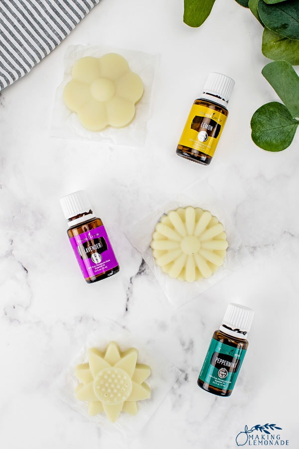 DIY lotion bars in the shape of flowers and bottles of essential oils.
