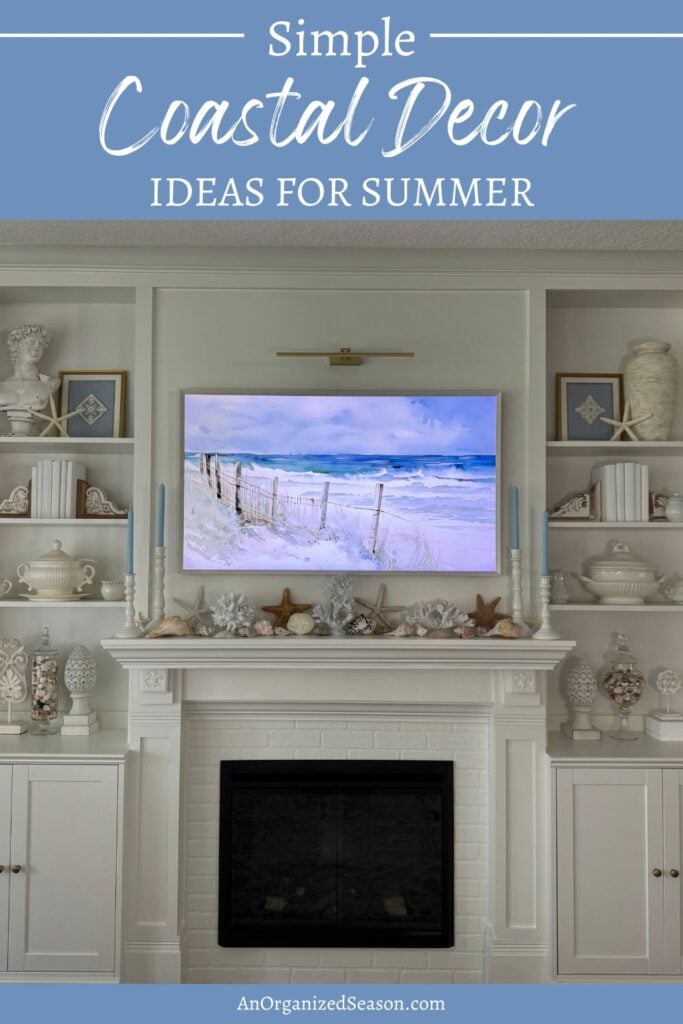 A white fireplace mantel decorated with Coastal Decor, featuring seashells, starfish, and vases. Above the mantel, a TV displays a beach scene with sand dunes. Text reads: Simple Coastal Decor Ideas for Summer.