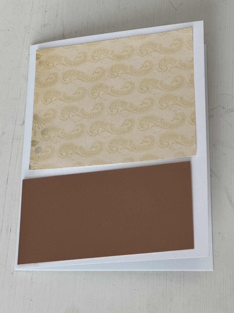 A white card with a piece of patterned cardstock and a brown rectangle. 