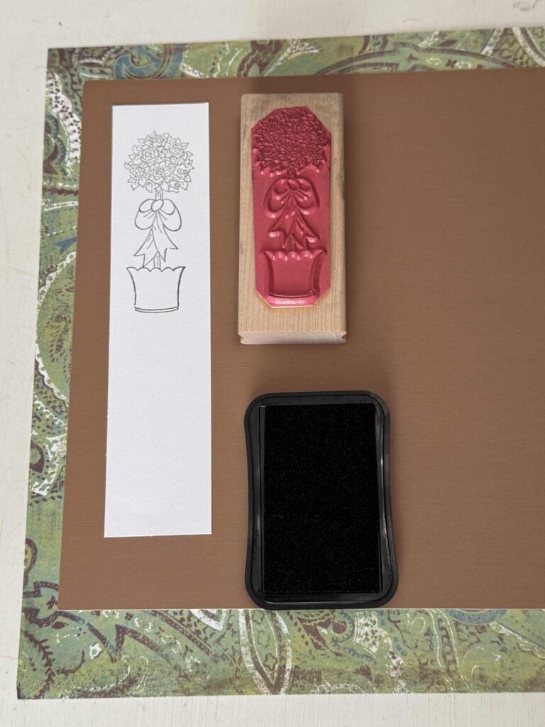 A topiary stamp on white paper next to a black ink pad and the stamp. 