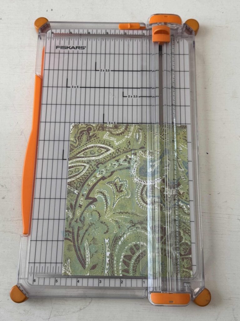 A Fiskars paper cutter with a piece of patterned cardstock. 
