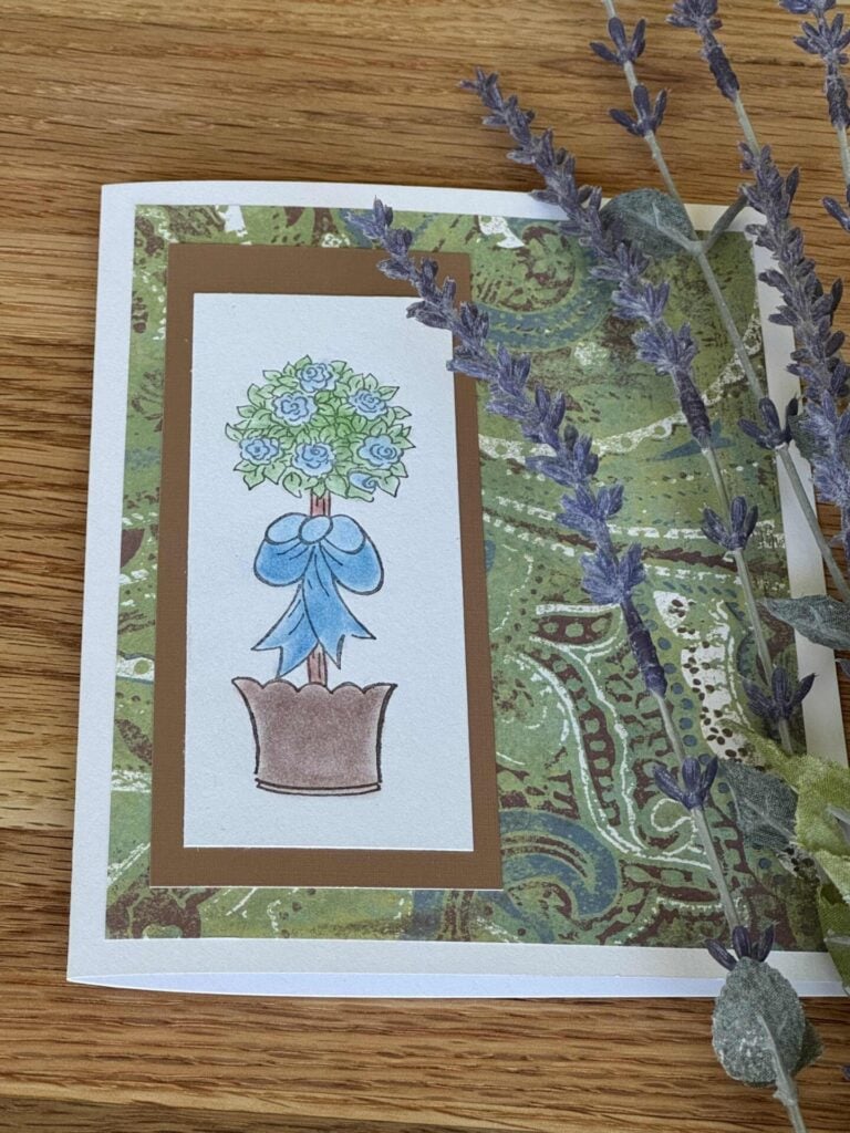 A handmade topiary card laying next to lavender. 