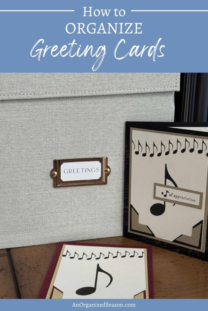 A fabric storage box labeled GREETINGS sits on a wooden surface next to two handmade greeting cards decorated with musical notes and a staff. Discover simple ways to organize greeting cards and keep your collection tidy.
