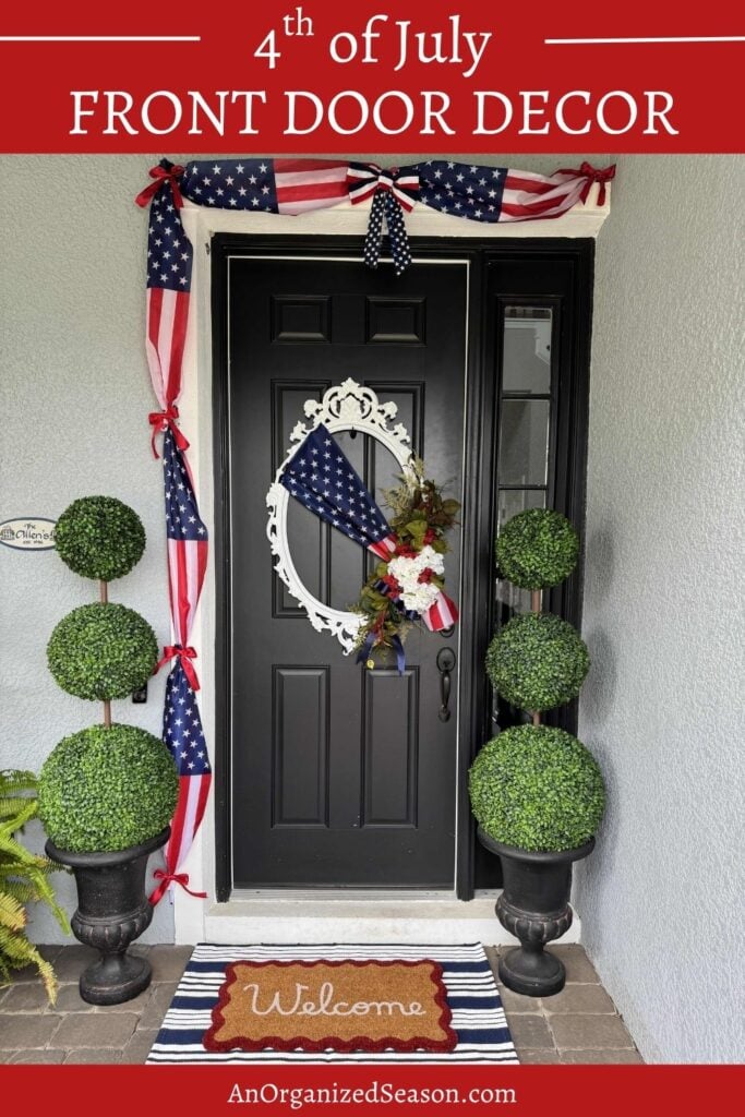 A black front door features festive 4th of July front door decor, including an American flag, a patriotic wreath, star-patterned bunting, two potted topiaries, and a Welcome doormat. The image is labeled Front Door Decor.
