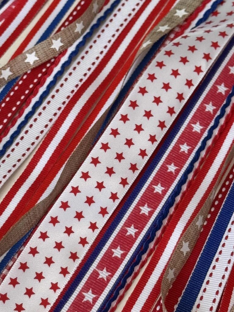 Close-up of various decorative ribbons in red, white, and blue—featuring stripes, stars, and dotted patterns that evoke an American theme.