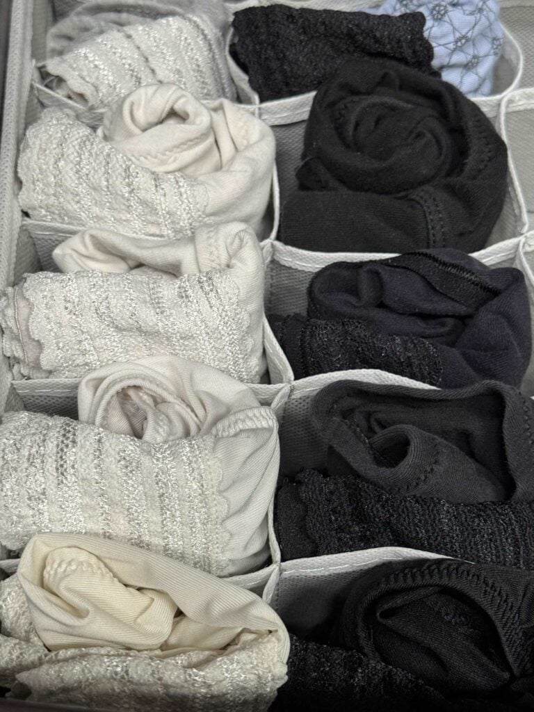 Rolled underwear organized by color in a compartmentalized drawer organizer.