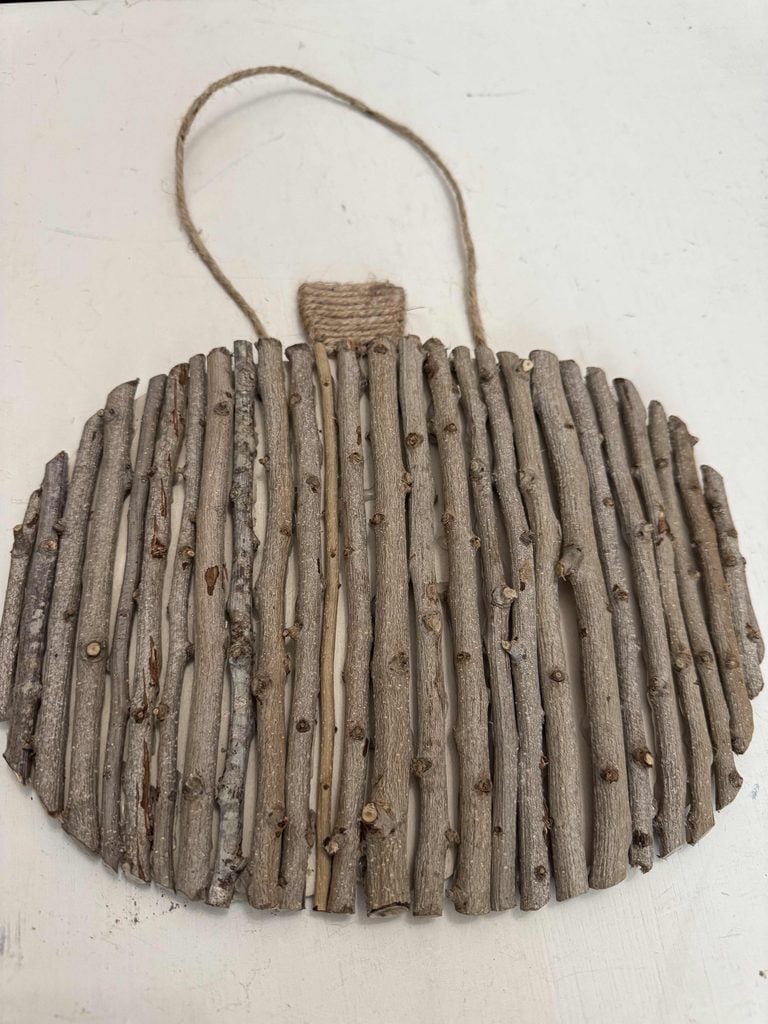 A DIY Twig Pumpkin-shaped decoration made from vertical sticks glued side by side, with a twine loop at the top for hanging and a twine-wrapped stem, set against a white background.